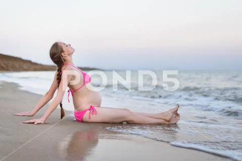 Young pregnant woman is relaxing on the seashore. Breathing sea. Deserted bea Stock Photos