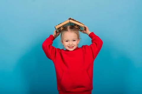 Young preschool child learns while reading a book, isolated on blue Stock Photos