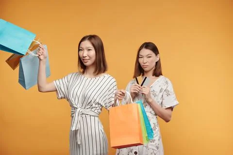 Young pretty Asian female consumers with paperbags enjoying shopping Stock Photos