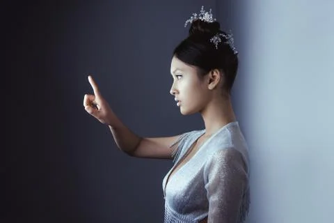 Young pretty asian futuristic woman pressing an imaginary button, empty space Stock Photos