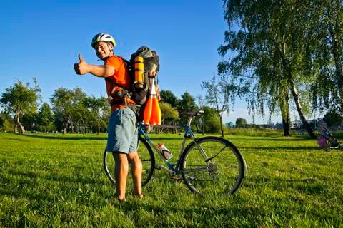 Young pretty athletic man standing with bicycle in colorful summer park. Foto stock