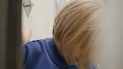 Young pretty blonde inside the fitting room puts on a blue sweater over her head Stock Footage 167178290