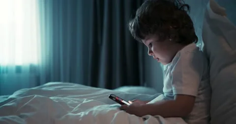 Young pretty boy sitting in white bed and search something on the phone. 4K Stock Footage 147943198