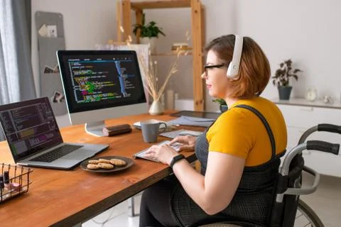 Young pretty female software developer in wheelchair working with data at home Stock Photos