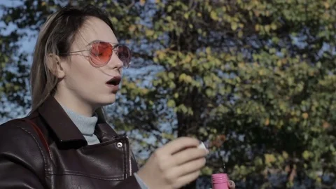 Young pretty girl blows soap bubbles, outdoor Vidéo 82455152