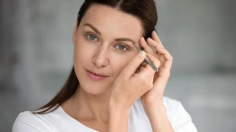 Young pretty lady doing eyebrows correction procedure. Stock Photos