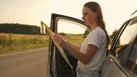 Young pretty lady is standing next to her car and looking for the best way on Stock Footage 217680664