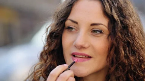 Young pretty lady using her lipstick in the street Stock Footage 62390339