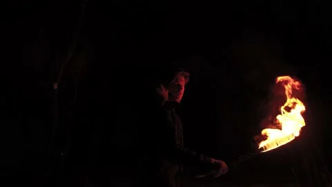 Young pretty man goes through night forest with a bright torch scared of dark Video stock 154763690