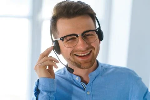 Young pretty man use headphones with microphone in office have serious busine Stock Photos