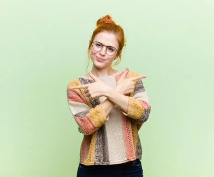 Young pretty red head woman looking puzzled and confused, insecure and pointi Stock Photos
