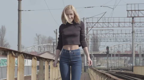 Young pretty shy model walking on the railway and smiling Stock Footage 63632577