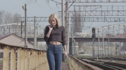 Young pretty shy model walking on the railway and smiling while windy Stock Footage 63633821