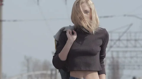 Young pretty shy model walking on the railway and smiling while windy Stock Footage 63636450