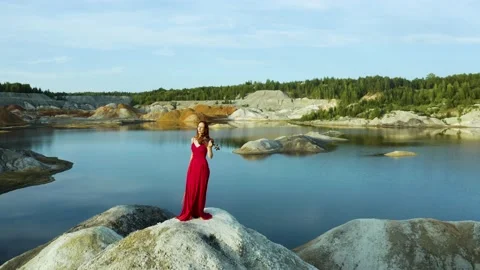 Young pretty slender red-haired woman with long hair in red dress playing violin 스톡 동영상 221031418