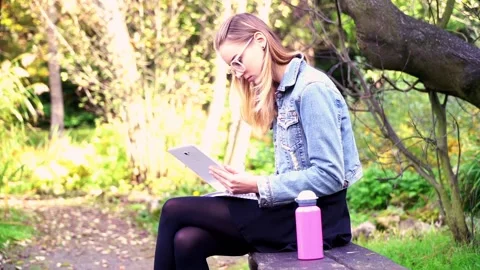 Young, pretty student working with tablet and notes in beautiful garden Stock Footage 85818574