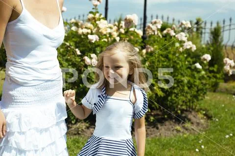 Young pretty woman with cute daughter in rose garden at summer happy smiling Stock-Fotos
