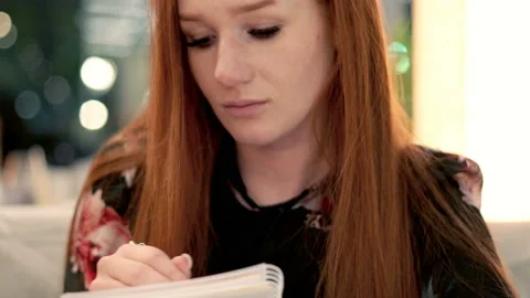 Young pretty woman doing notes in cafe Видео 100018040