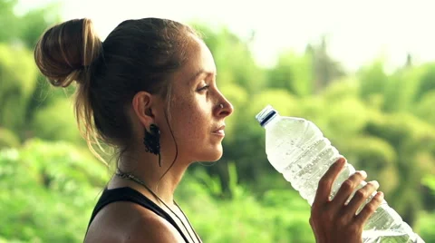 Young, pretty woman drinking water in park HD Stock Footage 54591158
