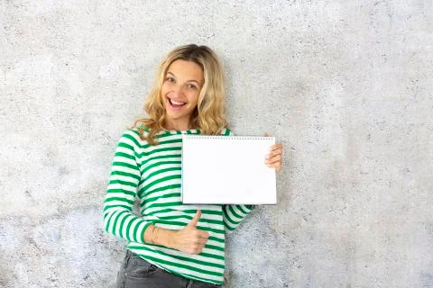 Young pretty woman with striped pullover holding blank, checkered paper block Stock Photos