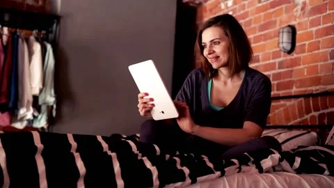 Young, pretty woman using tablet sitting on bed Stock-Footage 91333604