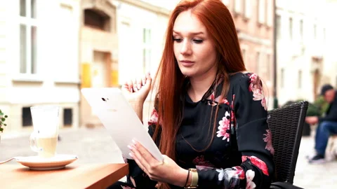 Young, pretty woman using tablet while sitting in cafe in the city, 4K Stock Footage 97035348