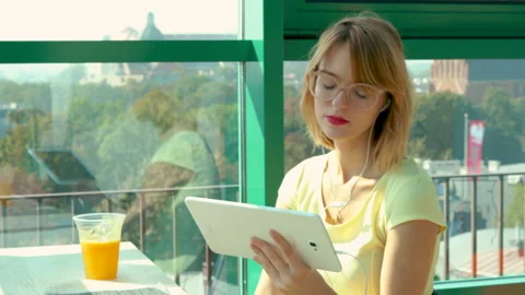 Young, pretty woman using tablet while sitting in cafe, 4K Stock Footage 107424625