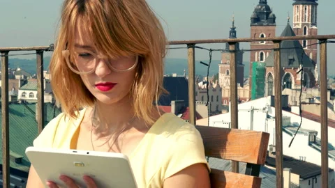 Young, pretty woman using tablet while sitting on terrace, 4K Stock Footage 107424816