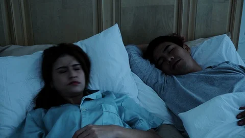 Young pretty woman woke up because of snoring husband Stock Footage 87446853