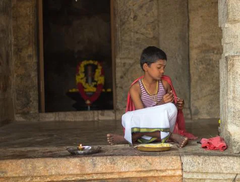 An Young Priest is seen sitting outside a Hindu Shiva temple. Stock Photos