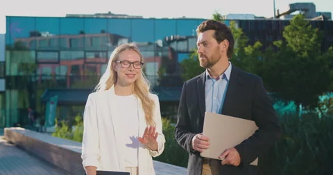 Young professional couple man and woman walking outdoors along modern glass Stock Footage 346236475
