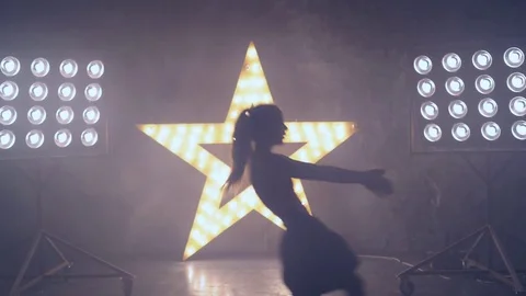 A young professional dancer performs a fast number on stage in the light of the Stock Footage 81707715