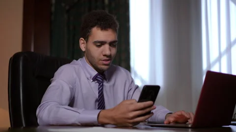 A young professional is deeply engaged with their smartphone while working Stock Footage 291541805