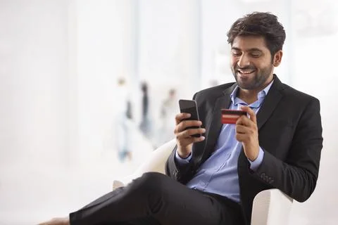 A YOUNG PROFESSIONAL DOING ONLINE TRANSACTION ON MOBILE PHONE Stock Photos