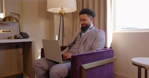 A Young Professional Engaged in Remote Work from a Chic and Stylish Hotel Room Stock Footage 295839450