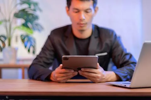 Young Professional Engaged in Tablet Use at Modern Office Workspace Stock Photos