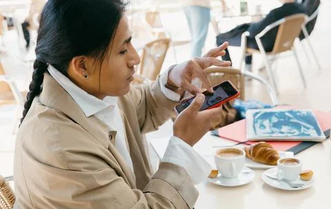 Young professional enjoying coffee while using smartphone. Stock Photos
