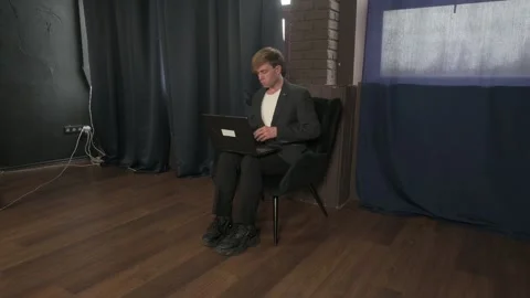 Young Professional Man Sitting in a Dark Modern Studio Working on Laptop Stock Footage 328497965