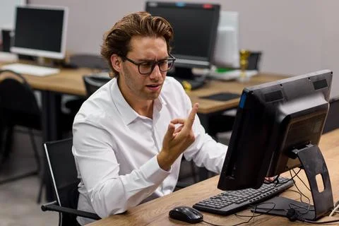 Young professional man typing at desktop computer in modern office training room Stock-Fotos