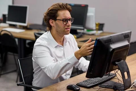 Young professional man typing at desktop computer in modern office training room Stock-Fotos