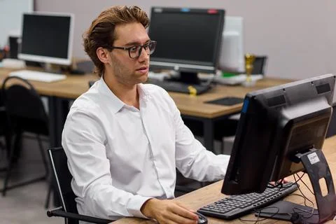 Young professional man typing at desktop computer in modern office training room Stock-Fotos