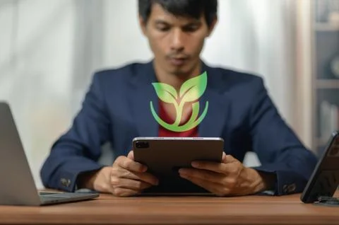 Young Professional Man Using Digital Tablet with Eco Leaf Overlay in Office.. Stock Photos