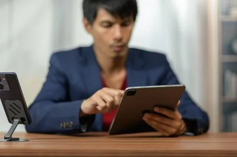 Young professional man using tablet computer in modern office setting Stockfoto's
