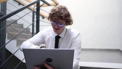 Young professional man working on laptop in office stairwell focused employee re Stock Footage 333973975