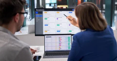 Young Professional Managing Spreadsheets And Documents Across Multiple Screen Foto stock