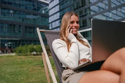 A young professional is seen actively working outdoors on a laptop in a vibrant Stock Photos