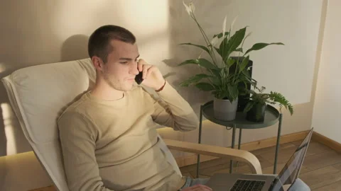 Young professional speaks on the phone while working on a laptop Stock Footage 142614523