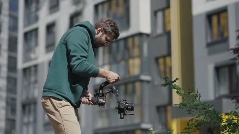 Young professional videographer with camera in his hands shoots video against Stock-Footage 244268336