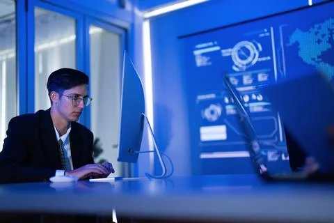 Young professional working on computer in a modern office with blue lightin.. Stock-Fotos