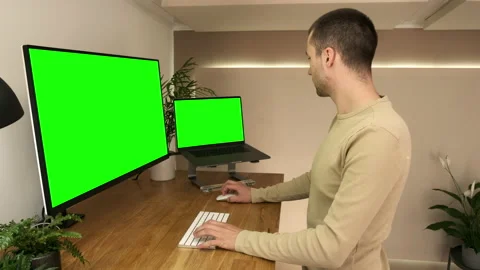 A young professional working from home uses a green screen laptop and screen Stock Footage 142609554